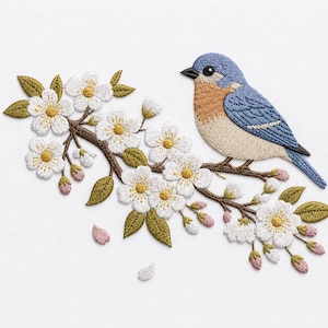 Può includere: Immagine ricamata di un uccello azzurro posato su un ramo fiorito. L'uccello presenta dettagli blu, beige e neri. Il ramo presenta fiori bianchi con centri gialli, foglie verdi e boccioli rosa, il tutto su sfondo bianco.