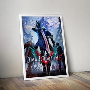 May include: A framed poster for "Devil May Cry 5." The image shows multiple characters in dynamic poses, with a central figure wielding a large sword. The poster has a white border and a dark, action-packed theme, suitable for a game room.