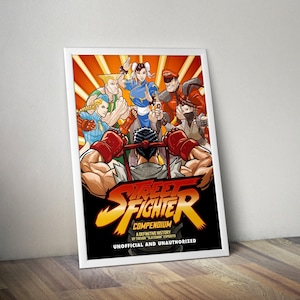 May include: A framed poster featuring a vibrant illustration of Street Fighter characters. The artwork showcases a dynamic composition with characters in action poses, set against a bold orange and black background. The title "Street Fighter Compendium" is prominently displayed.