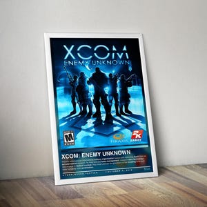 May include: A framed poster for the video game "XCOM: Enemy Unknown." The poster shows silhouetted soldiers against a blue and white backdrop. The game's title and logo are displayed at the top. The poster is leaning against a wall.