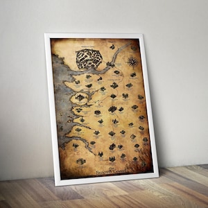 May include: Framed map print of the Sword Coast, featuring Baldur's Gate and other locations. The map has a vintage, parchment-like appearance with detailed illustrations and text. The print is in a white frame, leaning against a wall.