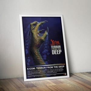 May include: A framed poster for the video game "X-COM: Terror From The Deep." The artwork features a large, clawed hand emerging from a dark blue background. The game's title is displayed in bold, white letters, with additional text below.