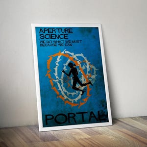 May include: Framed poster featuring the text "APERTURE SCIENCE" and "WE DO WHAT WE MUST BECAUSE WE CAN" above the word "PORTAL". The poster has a blue background with a silhouette of a person jumping through a white and orange design.