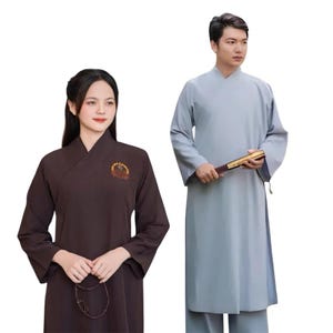 May include: Two individuals wearing traditional robes. One robe is a dark brown color with an embroidered emblem, and the other is a light blue color. The light blue robe is paired with matching pants. The image is set against a plain white background.