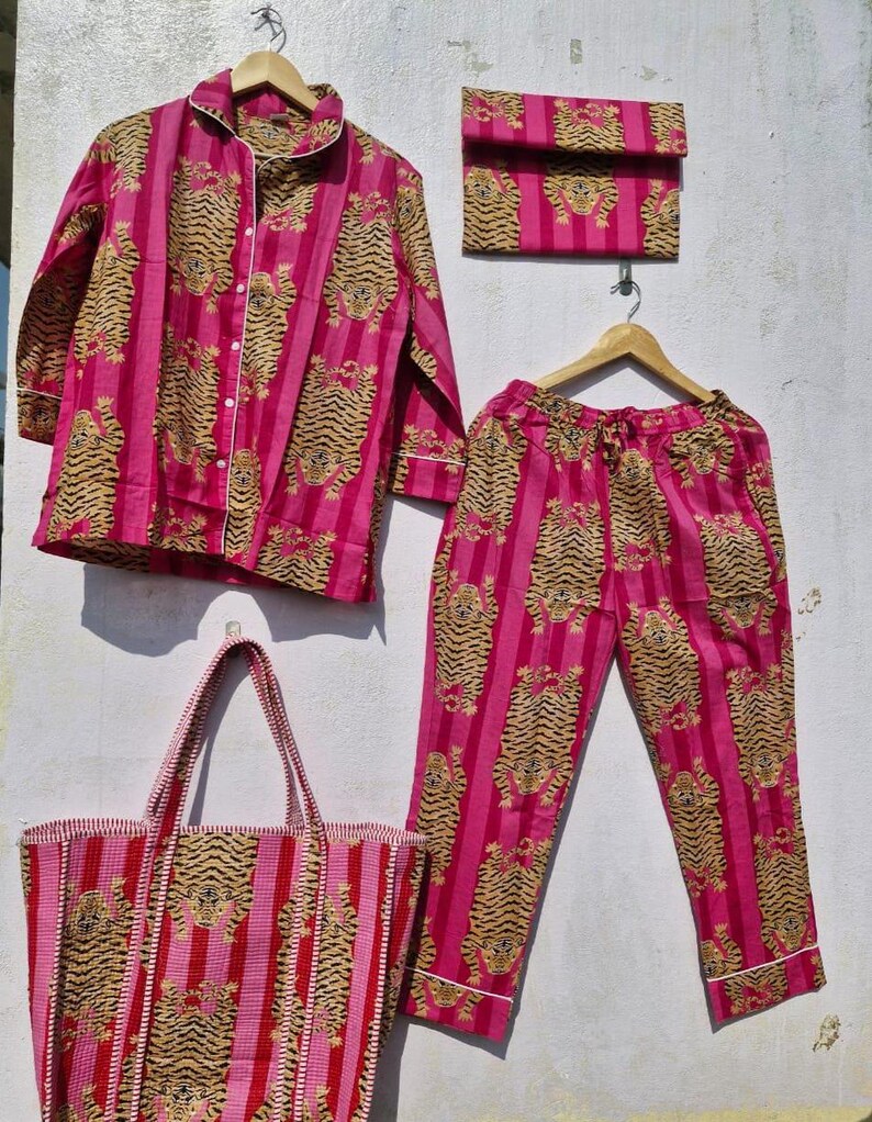 May include: A matching pink pajama set with a tiger print, including a button-down shirt, pants, and a small clutch. A tote bag with the same tiger print is also included. The set is made of a soft fabric and is perfect for lounging.