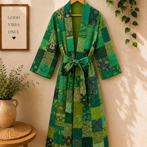 Puede incluir: Una bata de manga larga con un diseño de patchwork en varios tonos de verde. La prenda incluye un cinturón de tela a juego en la cintura y está confeccionada con múltiples paneles cuadrados con diversos patrones florales y geométricos.