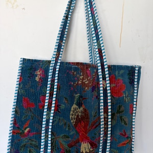 May include: Teal tote bag with a floral and bird pattern. The bag features a corduroy texture and white and teal striped handles. The design includes red flowers and a detailed bird illustration.