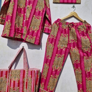 May include: A matching pajama set and tote bag in a vibrant pink hue, featuring a repeating pattern of tiger illustrations. The set includes a button-down shirt, pants, and a clutch. The tote bag has a striped design. All pieces have white trim.