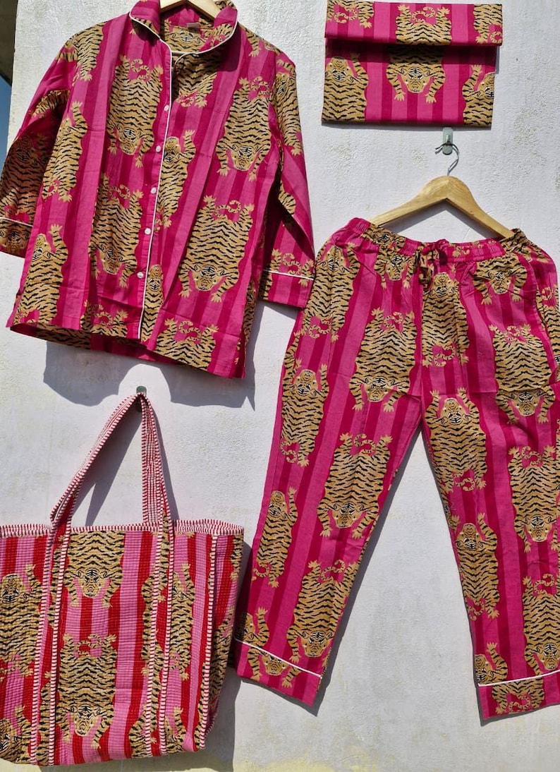 May include: A matching pajama set and tote bag in a vibrant pink hue, featuring a repeating pattern of tiger illustrations. The set includes a button-down shirt, pants, and a clutch. The tote bag has a striped design. All pieces have white trim.
