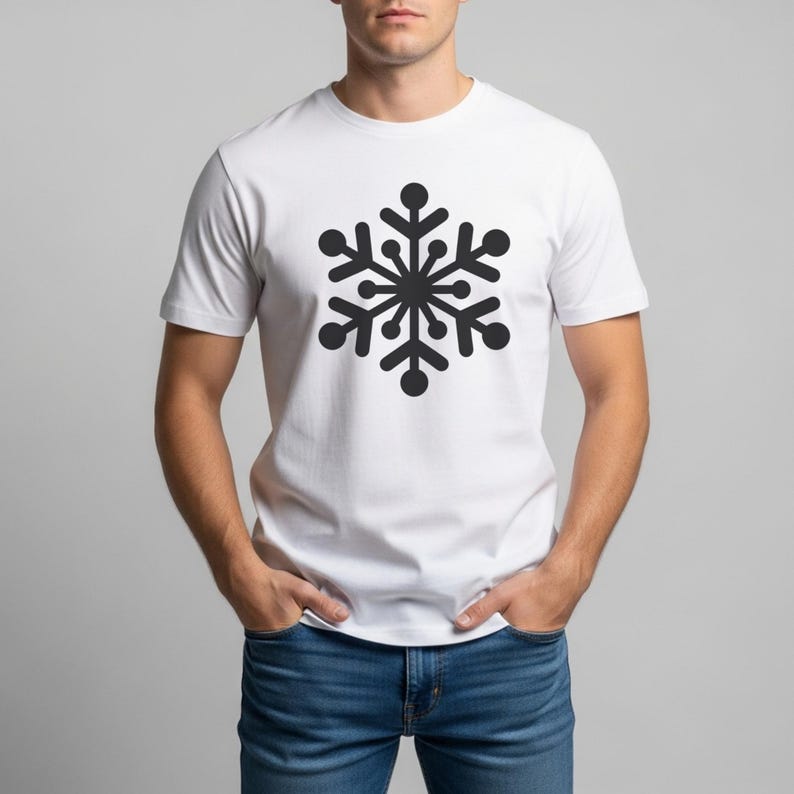 Op de afbeelding: Wit t-shirt met een groot zwart sneeuwvlokontwerp. De sneeuwvlok is een symmetrische illustratie met afgeronde uiteinden en een centraal cirkelvormig element. Het t-shirt heeft korte mouwen en wordt gedragen met een spijkerbroek.