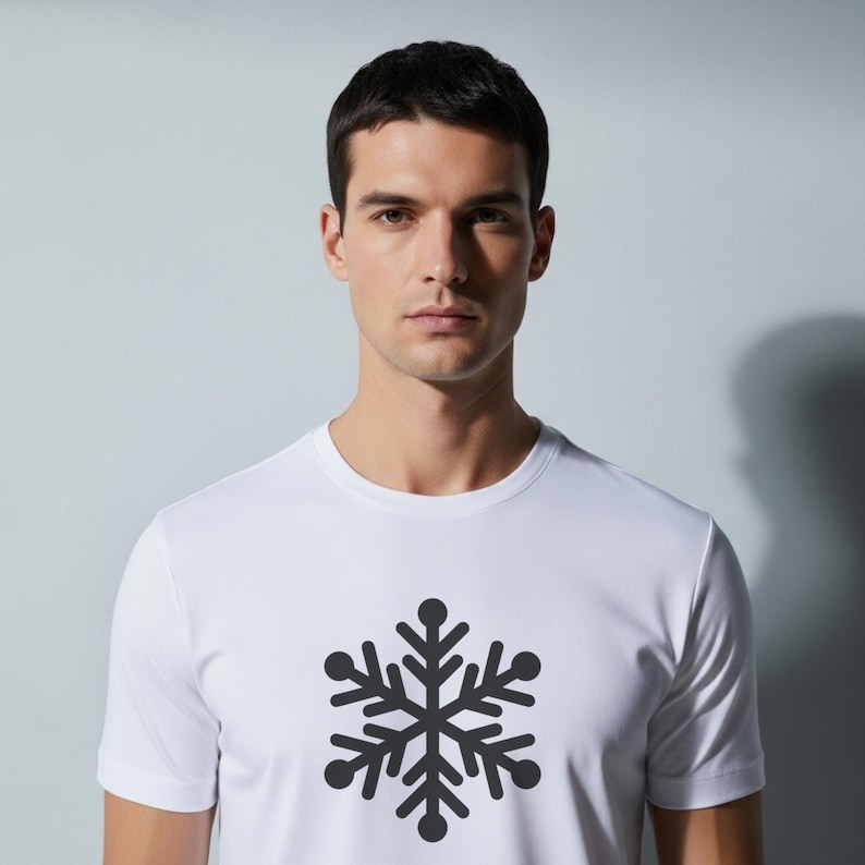 Op de afbeelding: Wit T-shirt met een donkergrijze sneeuwvlok op de voorkant. De sneeuwvlok is gecentreerd. Het shirt heeft een ronde hals en is gemaakt van een gladde, lichte stof.