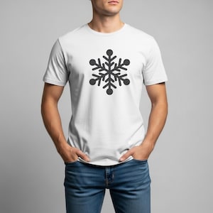 Op de afbeelding: Wit t-shirt met een zwart sneeuwvlokontwerp. De sneeuwvlok is gecentreerd en heeft een symmetrisch, zespuntig ontwerp met afgeronde uiteinden. Het shirt heeft korte mouwen en is gemaakt van een zachte stof.
