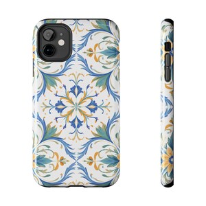 May include: A white phone case featuring a repeating floral pattern in blue, yellow, and green. The design includes stylized leaves and flower-like shapes, creating a decorative and elegant look. The case has a black border.