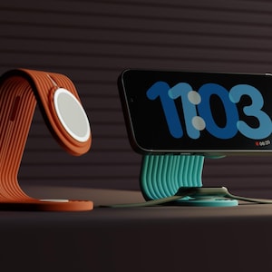 Puede incluir: Dos soportes de carga, uno naranja y blanco para un teléfono y otro para un smartwatch. El teléfono muestra la hora 11:03 en azul. La correa del smartwatch es verde.