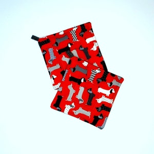 May include: Two red pot holders with a pattern of black and white dachshunds.