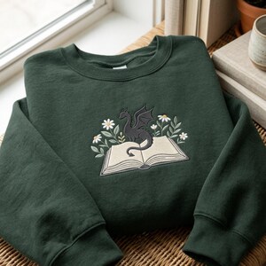 Felpa ricamata con drago e margherite, regalo ideale per gli amanti dei libri fantasy.