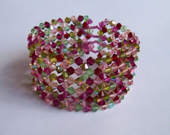 May include: A multi-strand bracelet made of pink, green, and clear faceted beads. The beads are arranged in a repeating pattern.