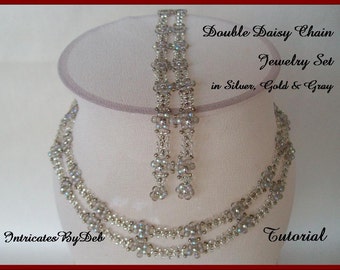 May include: A double daisy chain jewelry set in silver, gold, and gray. The set includes a necklace and earrings. The necklace is a double strand of beads with a daisy chain pattern. The earrings are long and dangle with a daisy chain pattern.