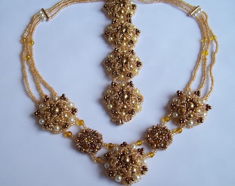 May include: A gold and cream beaded necklace with a matching pendant. The necklace has three strands of beads and the pendant is a cluster of beads in the shape of a flower.