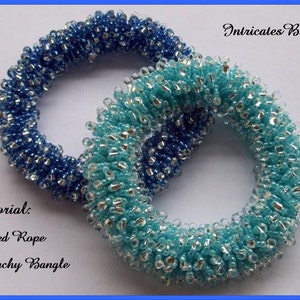 May include: Two beaded scrunchies in shades of blue and turquoise. The scrunchies are made with small, round beads and have a netted rope design. The text "Tutorial: Netted Rope Scrunchy Bangle" is visible in the image.