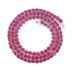 Könnte beinhalten: Eine schillernde Halskette mit einer Reihe von leuchtenden, runden, rubinroten Edelsteinen, die in einem silberfarbenen Metall gefasst sind. Die Edelsteine sind eng aneinander gesetzt und bilden ein durchgehendes, funkelndes Band. Der Hintergrund ist weiß.