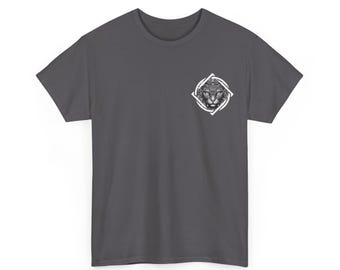 May include: Dark gray t-shirt featuring a detailed black and white illustration of a cat's face within a white diamond-shaped frame. The graphic is positioned on the upper left chest area of the shirt. The shirt has short sleeves and a crew neck.