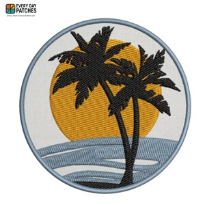 May include: A circular embroidered patch featuring a white background with a large yellow sun and two black palm tree silhouettes. The bottom section displays stylized light blue ocean waves. The entire design is bordered by a light blue stitched edge.