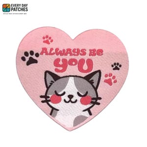 May include: A pink heart-shaped patch with the text "ALWAYS BE YOU" and a cartoon cat illustration. The patch features paw prints and the brand logo "EVERY DAY PATCHES".