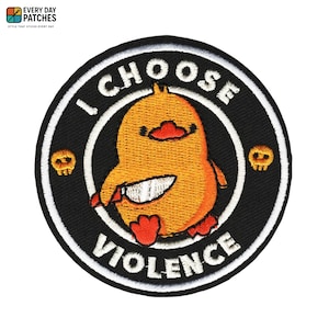 May include: Round embroidered patch with a cartoon chick wielding a knife, and the words "I CHOOSE VIOLENCE". The patch has a black background, white border, and two small skull graphics. The chick is orange and red.