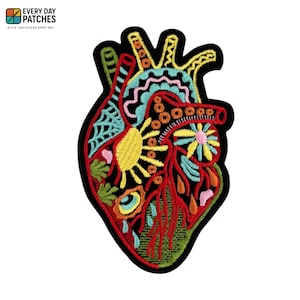 Puede incluir: Parche bordado con forma de corazón humano, con un diseño vibrante en colores rojo, amarillo, azul y verde. El parche tiene un borde negro e incluye el texto "EVERY DAY PATCHES" y "STYLE THAT STICKS EVERY DAY".