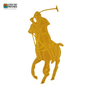 Puede incluir: Un parche bordado dorado que representa a un jugador de polo a caballo, sosteniendo un mazo. El parche tiene un diseño detallado y está sobre un fondo blanco. El parche tiene el texto "EVERY DAY PATCHES" y "STYLE THAT STICKS EVERY DAY".
