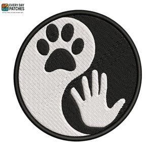 Op de afbeelding: Geborduurde patch met een Yin en Yang-ontwerp, met een pootafdruk en een hand. De ronde patch heeft een zwarte rand en een wit en zwart ontwerp. De tekst "EVERY DAY PATCHES" staat bovenaan.