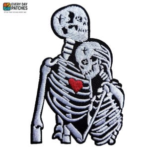 Könnte beinhalten: Gestickter Aufnäher mit zwei sich umarmenden Skeletten und einem roten Herz in der Mitte. Die Skelette sind weiß mit schwarzen Umrissen, vor einem schwarzen Hintergrund. Der Aufnäher hat oben den Text "EVERY DAY PATCHES".