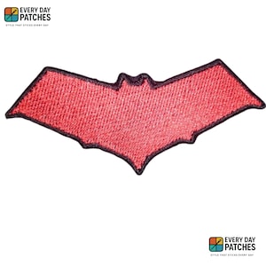 Może przedstawiać: Czerwona naszywka w kształcie nietoperza z czarną obwódką. Naszywka ma teksturowany wygląd i prawdopodobnie jest wykonana z tkaniny. Słowa "EVERY DAY PATCHES" i "STYLE THAT STICKS EVERY DAY" są wydrukowane u góry i u dołu obrazu.