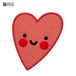 May include: A coral-colored heart-shaped patch with a smiling face. The patch has a textured appearance and a red border. The face features black eyes and red cheeks. The text "EVERY DAY PATCHES" and "STYLE THAT STICKS EVERY DAY" is in the top left corner.