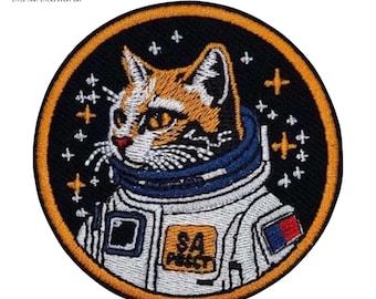 May include: Round embroidered patch featuring a cat in an astronaut suit. The cat has orange and white fur, a blue collar, and a white spacesuit. The patch has a black background with stars and the text "SA PUSSY".
