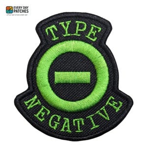 May include: Black embroidered patch with the words "TYPE NEGATIVE" in green, surrounding a green circle with a horizontal line. The patch has a black border and is likely for clothing or accessories.