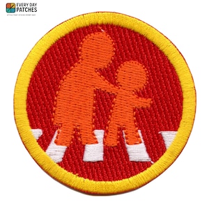 Può includere: Toppa ricamata con sfondo rosso e bordo giallo. La toppa presenta un'illustrazione arancione di due figure che attraversano un attraversamento pedonale. Il testo "EVERY DAY PATCHES" e "STYLE THAT STICKS EVERY DAY" è in alto.