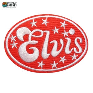 以下が含まれることがあります： 赤い楕円形のパッチで、白い刺繍で「Elvis」と書かれています。パッチは白い星に囲まれ、白い縁取りがあります。このパッチは、衣類やアクセサリーにアイロンで接着したり、縫い付けたりするためのものです。