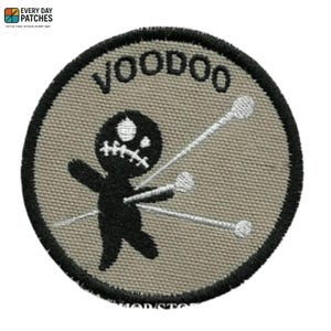 May include: Round patch with the word "VOODOO" in black, featuring a black voodoo doll with white pins. The patch has a tan background and a black border. The patch is from Every Day Patches.