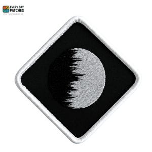 Pode incluir: Um patch bordado em preto e branco em forma de losango. O patch apresenta um design de lua crescente com uma borda branca. O texto "EVERY DAY PATCHES" e "STYLE THAT STICKS EVERY DAY" está no canto superior esquerdo.