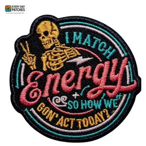 Puede incluir: Parche bordado con fondo negro y diseño circular. El parche presenta un esqueleto amarillo haciendo el signo de la paz. El texto dice "I match energy, so how we gon' act today?" en rosa, blanco y turquesa.
