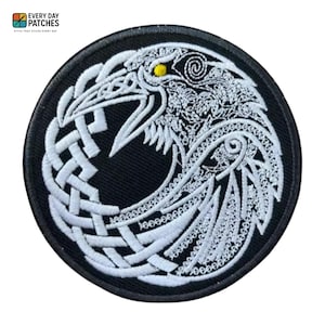 Könnte beinhalten: Runder schwarzer Aufnäher mit einem weißen Raben-Design. Der Rabe ist mit komplizierten Knotenmustern und einem gelben Auge bestickt. Der Aufnäher trägt den Text "EVERY DAY PATCHES" und "STYLE THAT STICKS EVERY DAY".