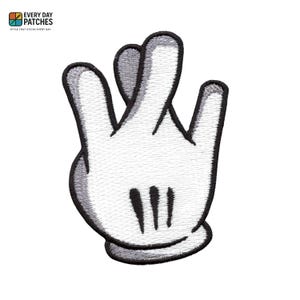 May include: Embroidered white glove patch with black outlines and details. The patch features a hand gesture with the index and middle fingers crossed. The patch has the text "EVERY DAY PATCHES" and "STYLE THAT STICKS EVERY DAY".