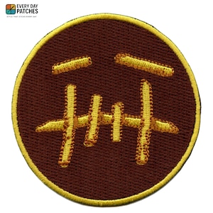 May include: Embroidered patch with a brown circular background and a yellow border. The patch features a yellow stitched design resembling a stylized face. The text "EVERY DAY PATCHES" is at the top left.