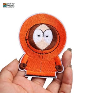 May include: Embroidered patch featuring the character Kenny from South Park. The patch is orange with a brown hood and gloves, and a white face. The patch has the text "EVERY DAY PATCHES" at the top.