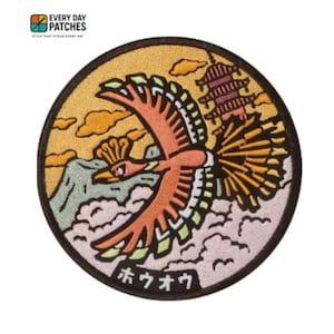 May include: A circular embroidered patch featuring a stylised orange and yellow bird in flight above white clouds and a mountain. A multi-tiered pagoda stands in the background against a yellow sky. The Japanese text "ホウオウ" is at the bottom.