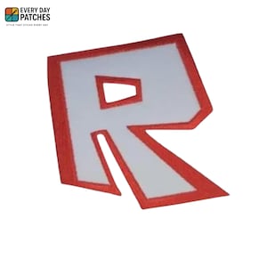 Può includere: Toppa ricamata con la lettera "R" bianca e un contorno rosso. La toppa ha una forma rettangolare con un design stilizzato. La toppa ha il testo "EVERY DAY PATCHES" in alto a sinistra.