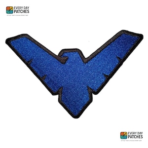 Puede incluir: Un parche bordado azul con un borde negro, que presenta un diseño de ala estilizado. El parche incluye el texto "EVERY DAY PATCHES" y "STYLE THAT STICKS EVERY DAY".