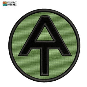 May include: Embroidered patch featuring a black "A" with a horizontal bar and arrow-like top, centered on a green circular background. The patch is bordered by a black stitched edge. The text "EVERY DAY PATCHES" and "STYLE THAT STICKS EVERY DAY" is in the top left corner.